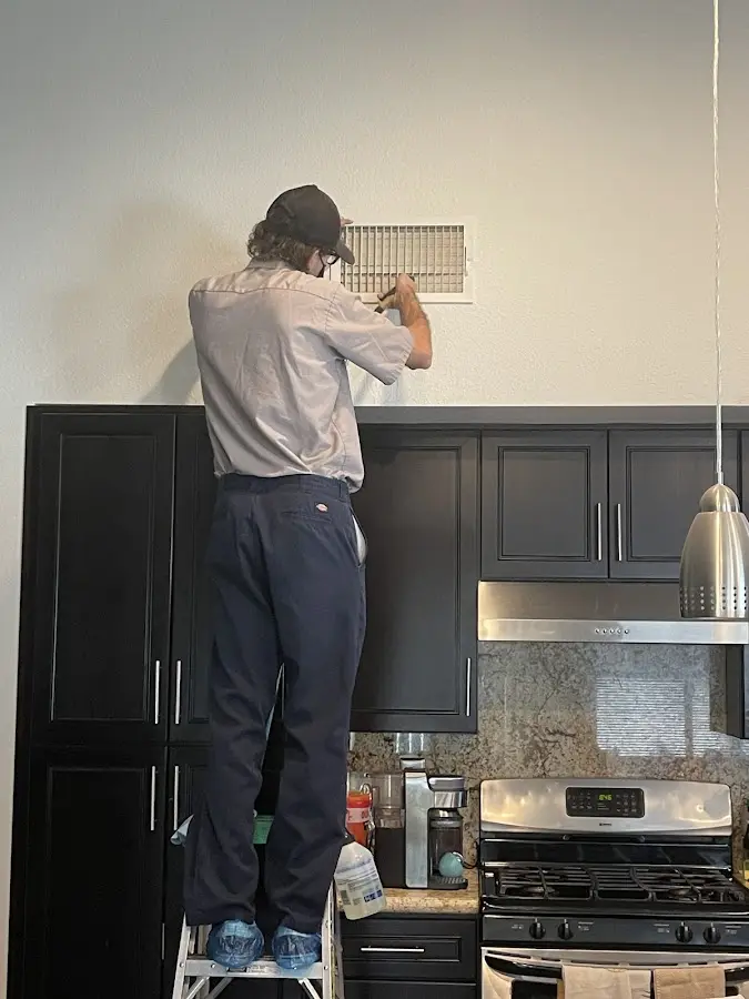 Technician inspecting an air vent during HVAC service in Niles